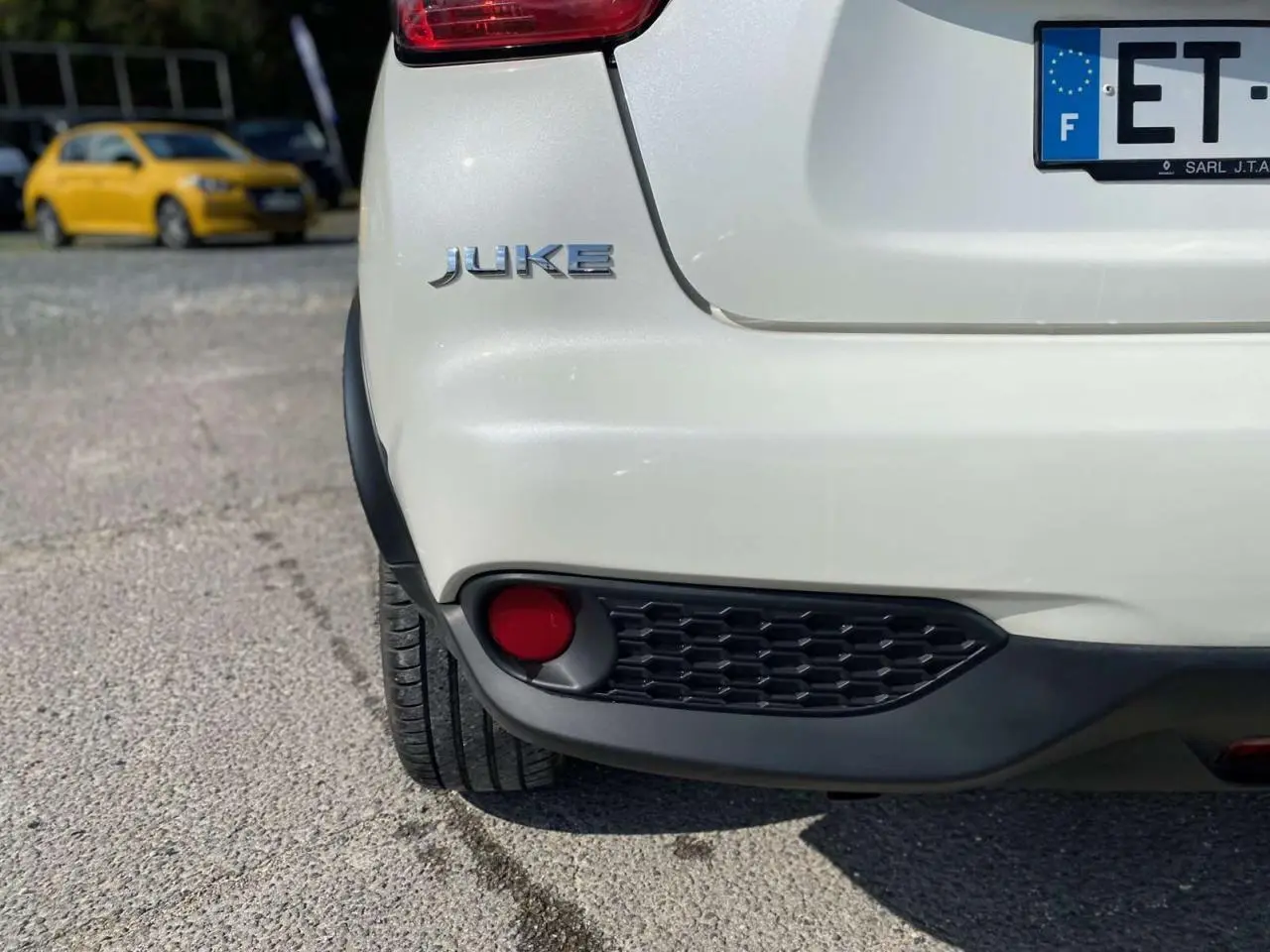Gros plan sur l’arrière gauche blanc métallisé du Nissan Juke 2017 avec feu antibrouillard et logo visible.