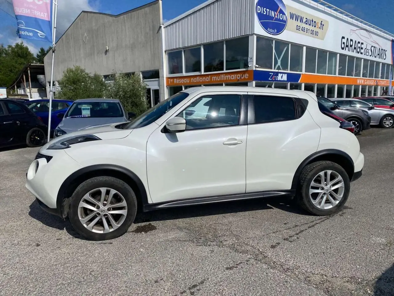 Vue de profil côté gauche d'un Nissan Juke blanc métallisé 2017 avec jantes alliage 17 pouces sur parking extérieur.