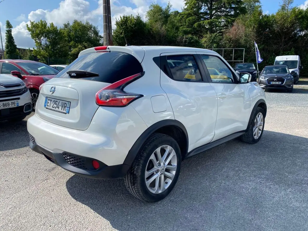 Nissan Juke blanc vue 3/4 arrière droit, vitres arrière surteintées et jantes alliage 17 pouces sport.