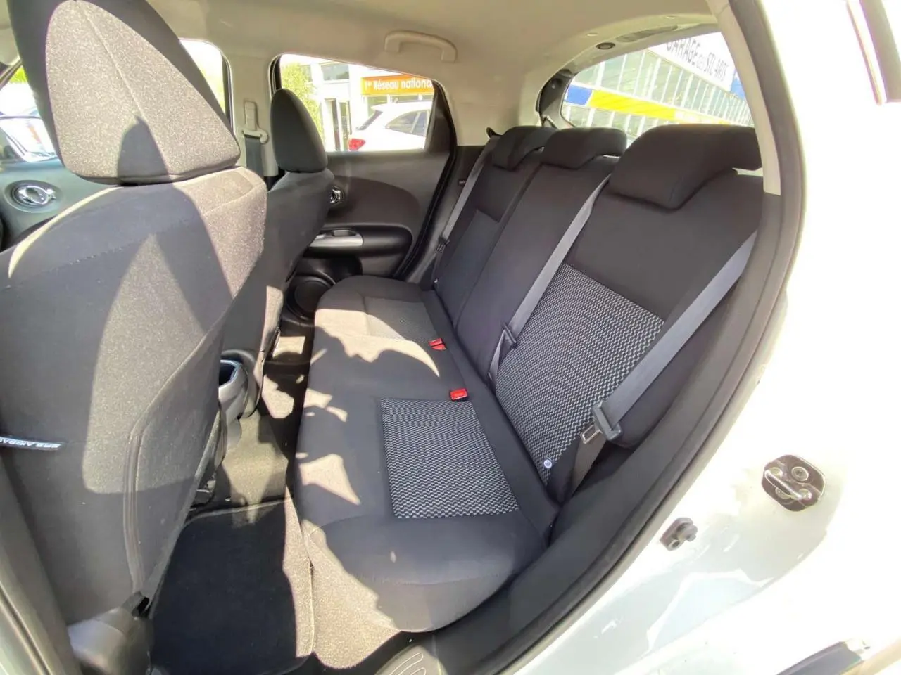 Vue intérieure côté droit sur la banquette arrière noire du Nissan Juke blanc 2017 avec ceinture de sécurité visible.