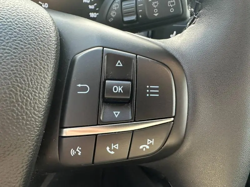 Gros plan sur les commandes multifonctions du volant cuir noir de la Ford Focus Titanium 2023.