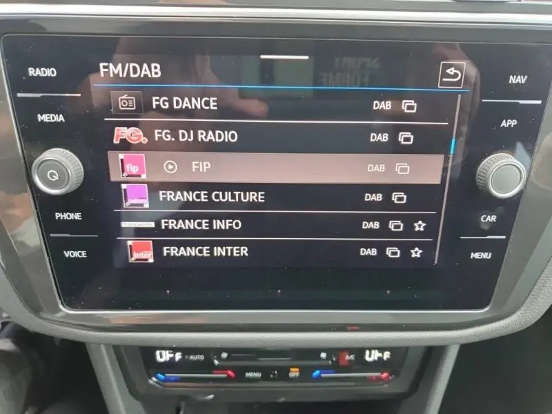 Écran tactile central du Volkswagen Tiguan 1.4 eHybrid 2022 affichant les stations radio FM/DAB, intérieur noir.