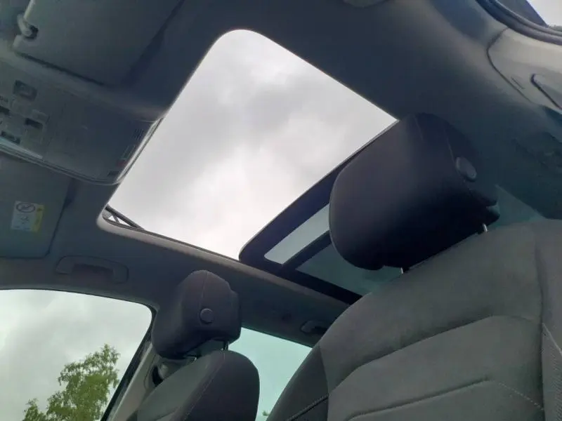 Vue intérieure du toit panoramique ouvert et des sièges avant noirs du Volkswagen Tiguan 1.4 eHybrid 2022.