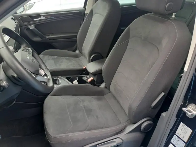 Vue intérieure côté gauche du Volkswagen Tiguan 2022, sièges avant sport en tissu gris foncé.