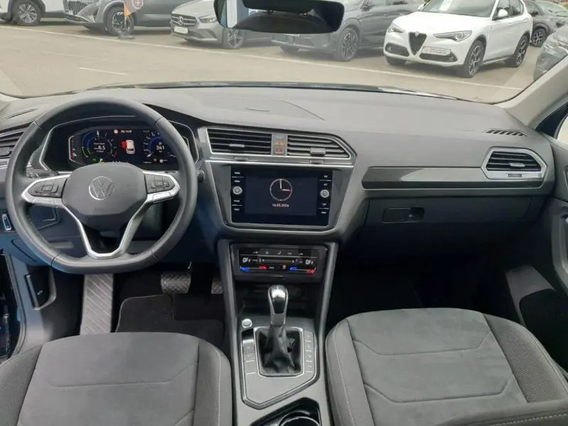 Vue intérieure avant du Volkswagen Tiguan 1.4 eHybrid 2022, tableau de bord noir avec écran tactile et volant multifonction.