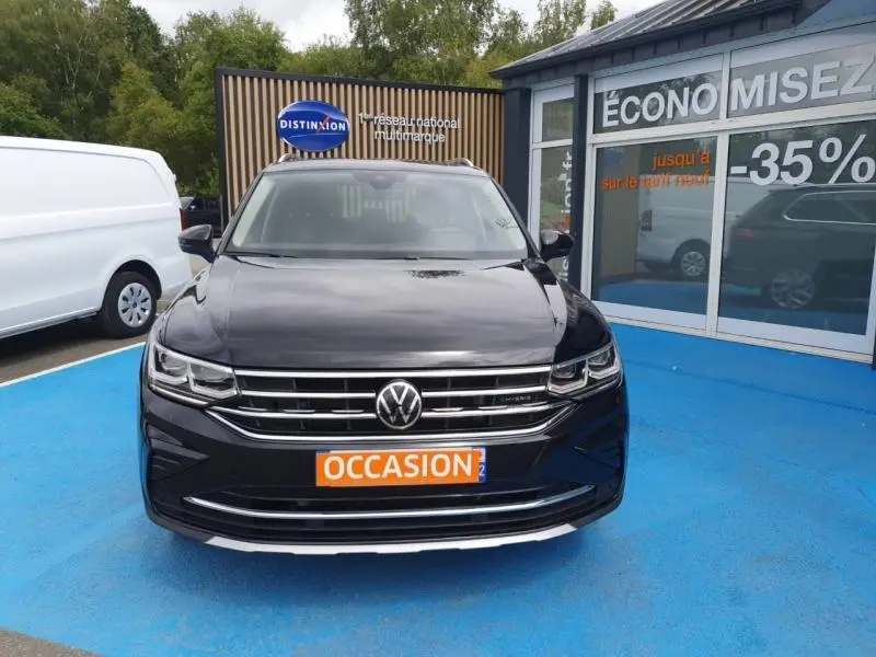 Vue avant d'un Volkswagen Tiguan 1.4 eHybrid noir intense nacré, avec calandre chromée et plaque "OCCASION".