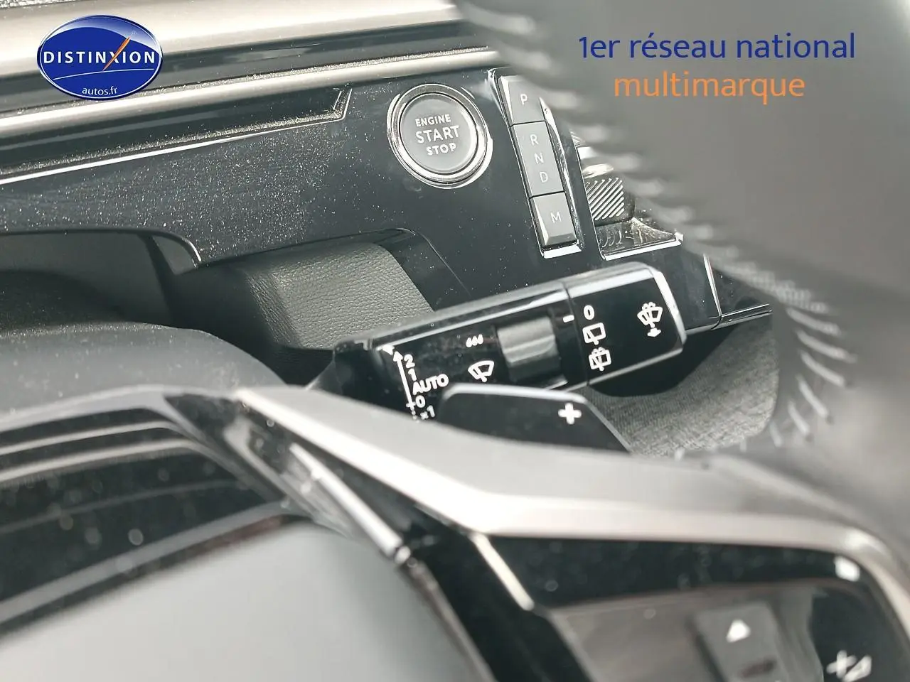 Détail intérieur du tableau de bord du Peugeot 5008 Hybrid bleu, avec bouton start/stop et commandes de vitres.
