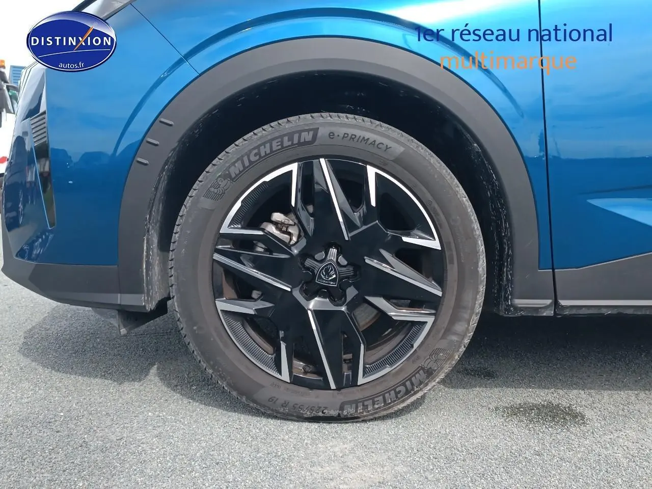 Gros plan sur la roue avant gauche d’un Peugeot 5008 bleu 2025 avec jante alu noire et détails Michelin.