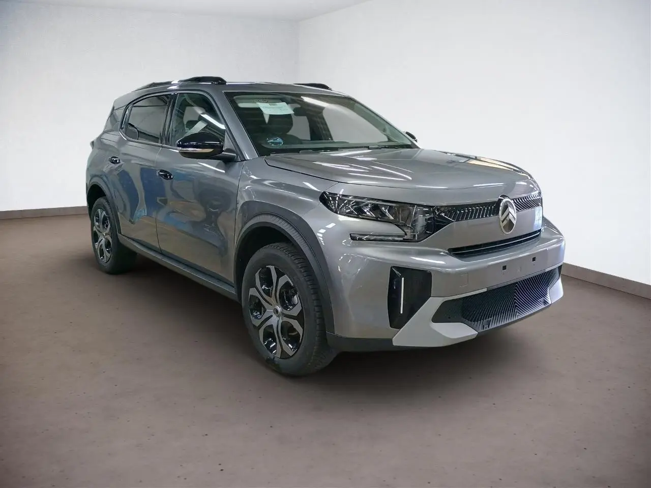 Vue 3/4 avant droit du Citroën C3 Aircross Hybrid 145 gris Mercury avec barres de toit noires et vitres surteintées.