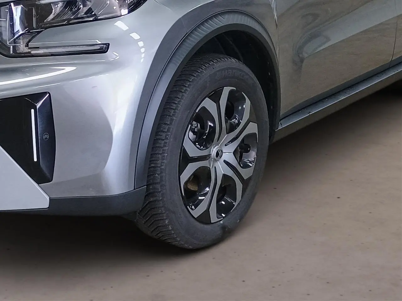 Gros plan sur la roue avant droite et partie du pare-chocs gris Mercury du Citroën C3 Aircross 2025 hybride.