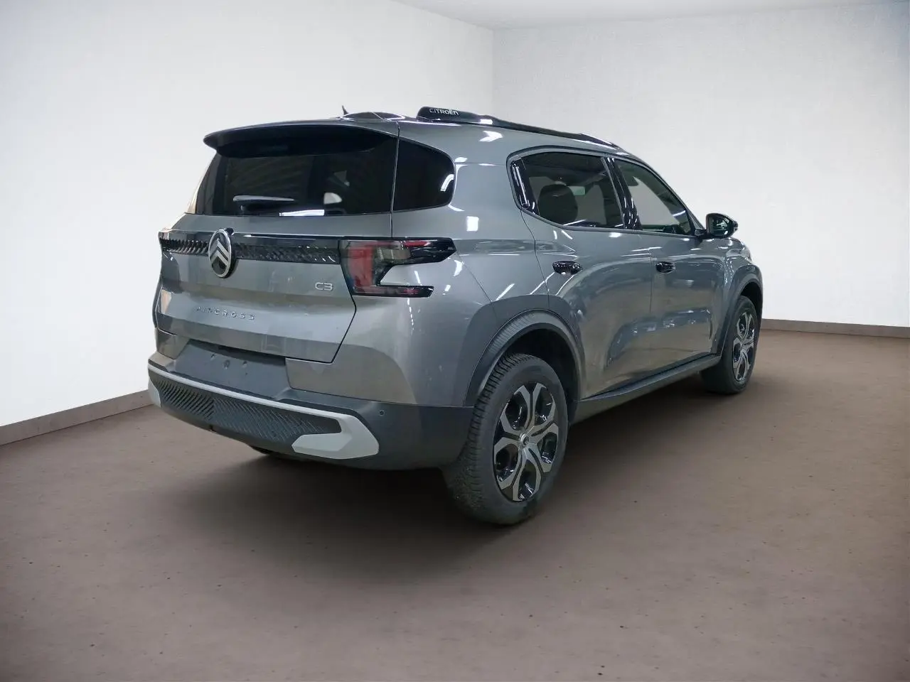 Vue 3/4 arrière droite du Citroën C3 Aircross gris Mercury avec barres de toit noires et vitres surteintées.