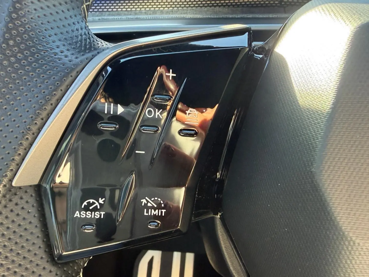 Gros plan sur les commandes au volant noir du Peugeot 5008 Hybrid 145ch GT, côté gauche.