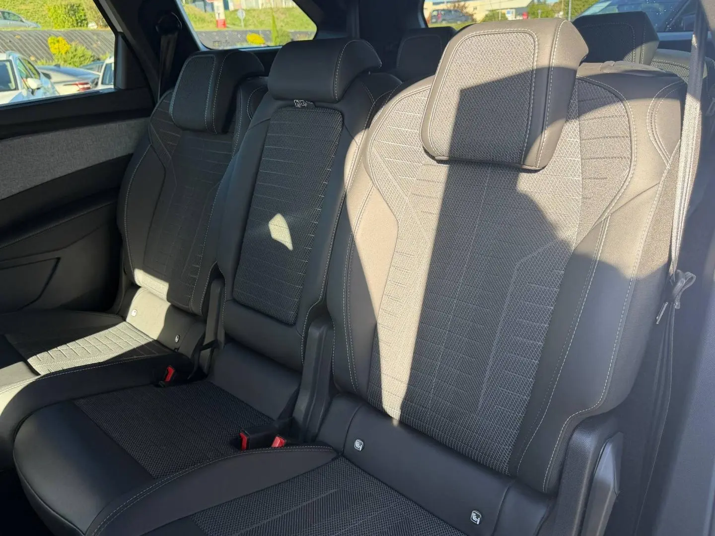 Vue rapprochée des sièges arrière noirs en tissu et cuir du Peugeot 5008 Hybrid 2025, avec appuis-tête et ceintures visibles.