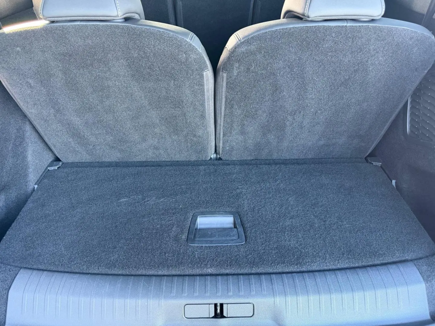 Vue rapprochée du coffre arrière du Peugeot 5008 Hybrid blanc, montrant la banquette arrière rabattue et le plancher de coffre fermé.