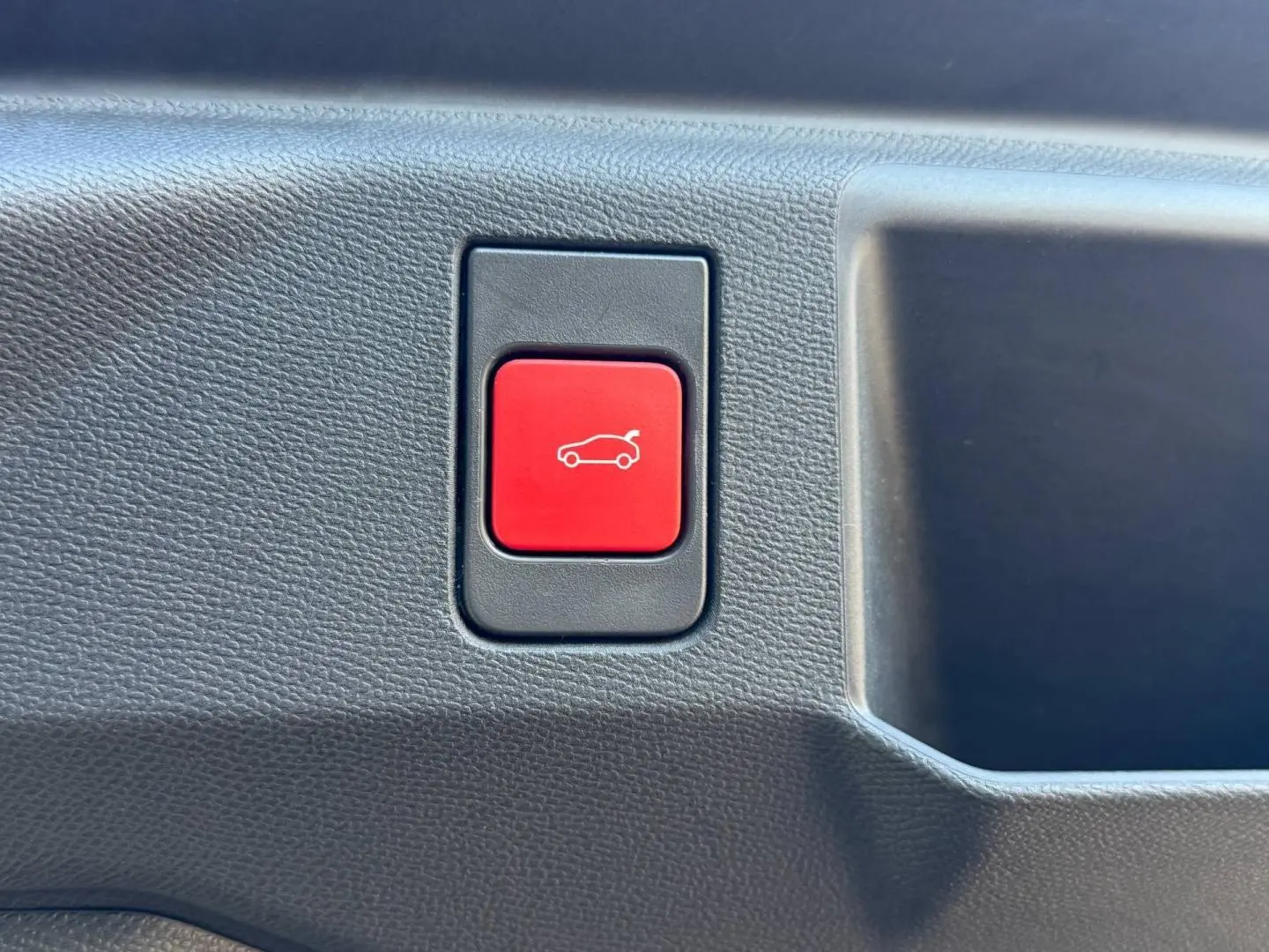 Gros plan sur le bouton rouge d'ouverture électrique du coffre du Peugeot 5008 Hybrid blanc Okénite.