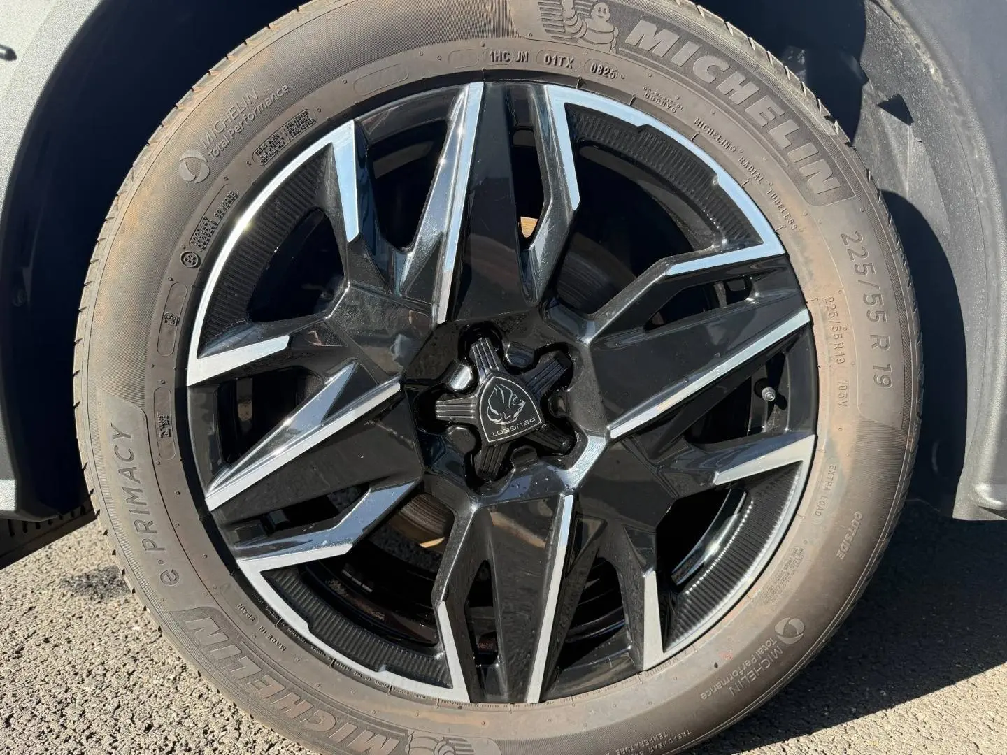 Gros plan sur la jante noire et argentée d’un Peugeot 5008 Hybrid blanc, avec pneu Michelin visible.