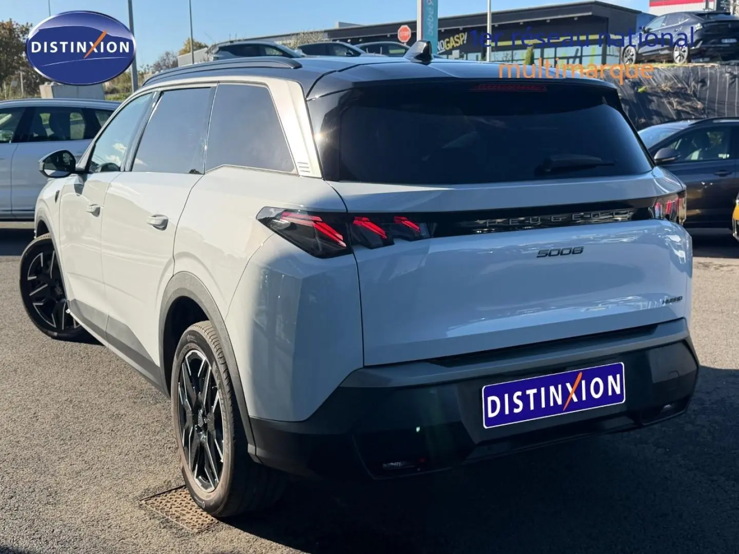 Vue 3/4 arrière droite d’un Peugeot 5008 Hybrid blanc Okénite avec feux arrière LED et jantes noires.
