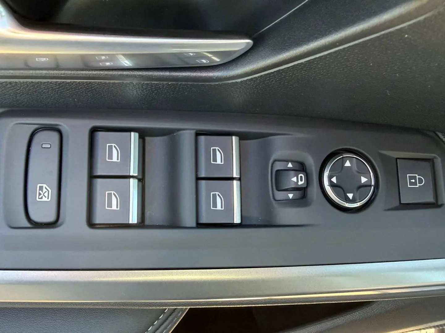 Gros plan sur les commandes de lève-vitres et réglages des rétroviseurs côté conducteur du Peugeot 5008 Hybrid blanc.