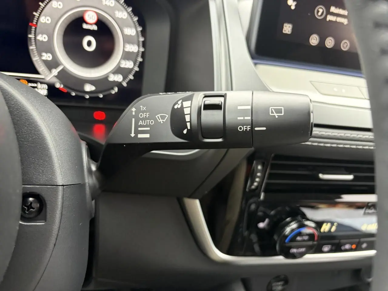 Gros plan sur la commande d’essuie-glace à gauche du volant dans l’habitacle du Nissan Qashqai gris foncé.