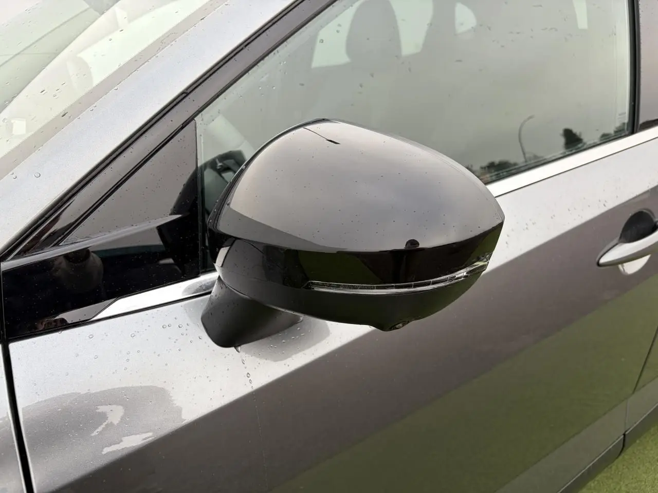 Rétroviseur côté gauche noir brillant sur Nissan Qashqai III gris foncé métallisé sous pluie légère.