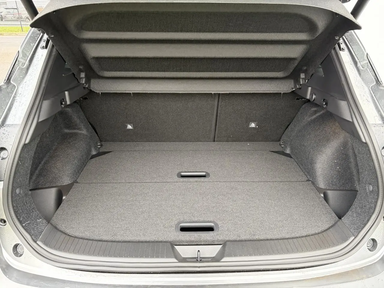 Coffre ouvert vu de l'arrière du Nissan Qashqai III gris foncé, plancher plat et habillage intérieur sombre.