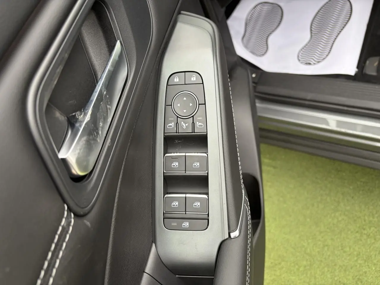 Gros plan sur la commande des vitres et rétroviseurs côté gauche du Nissan Qashqai 2025 gris foncé.