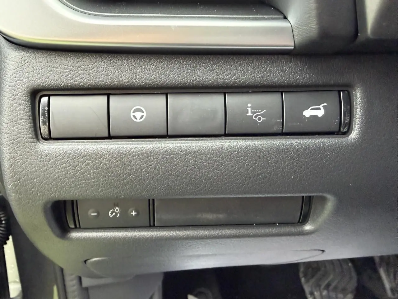 Gros plan sur les commandes intérieures noires du Nissan Qashqai 2025, côté conducteur, avec boutons de réglage et ouverture hayon.