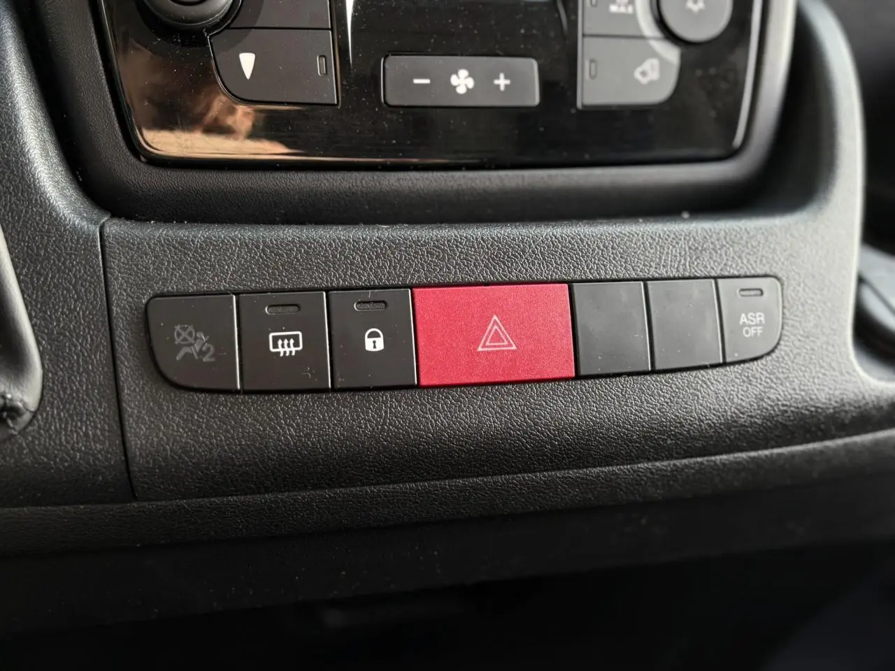 Gros plan sur les boutons de commande noirs et rouge du tableau de bord de l'Opel Movano Fourgon blanc de 2024.