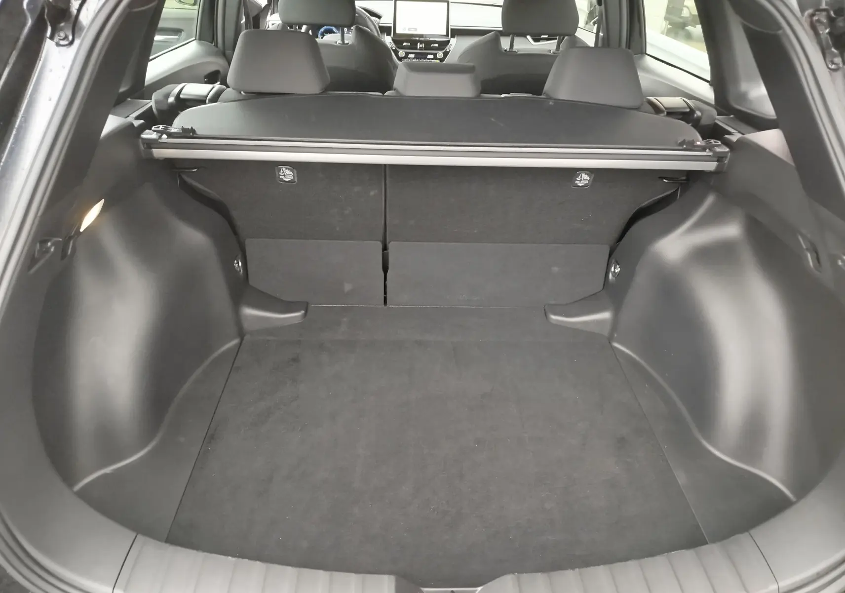 Coffre ouvert de la Toyota Corolla Cross noir intense, vue arrière montrant l'espace de chargement et la plage arrière.