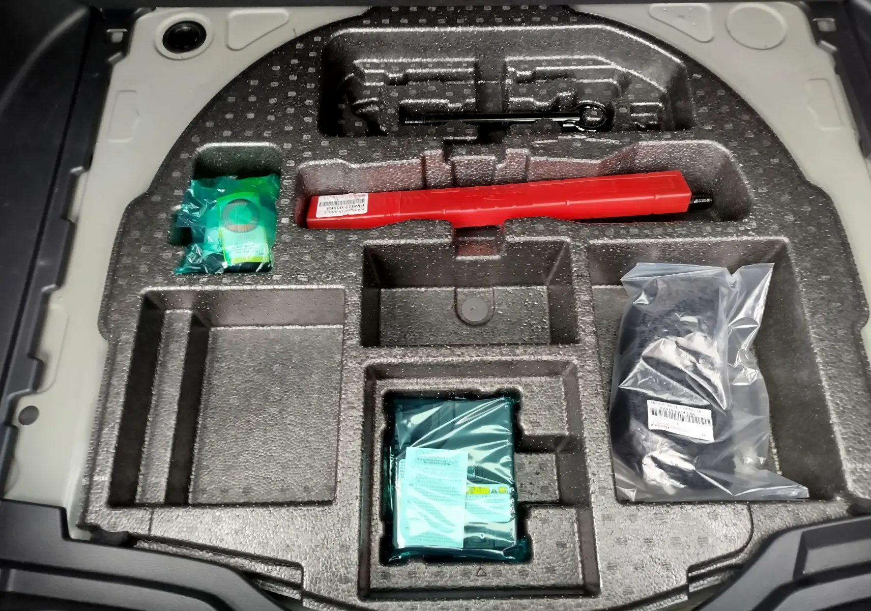 Rangement en mousse dans le coffre du Toyota Corolla Cross 2025, contenant des outils et accessoires emballés.