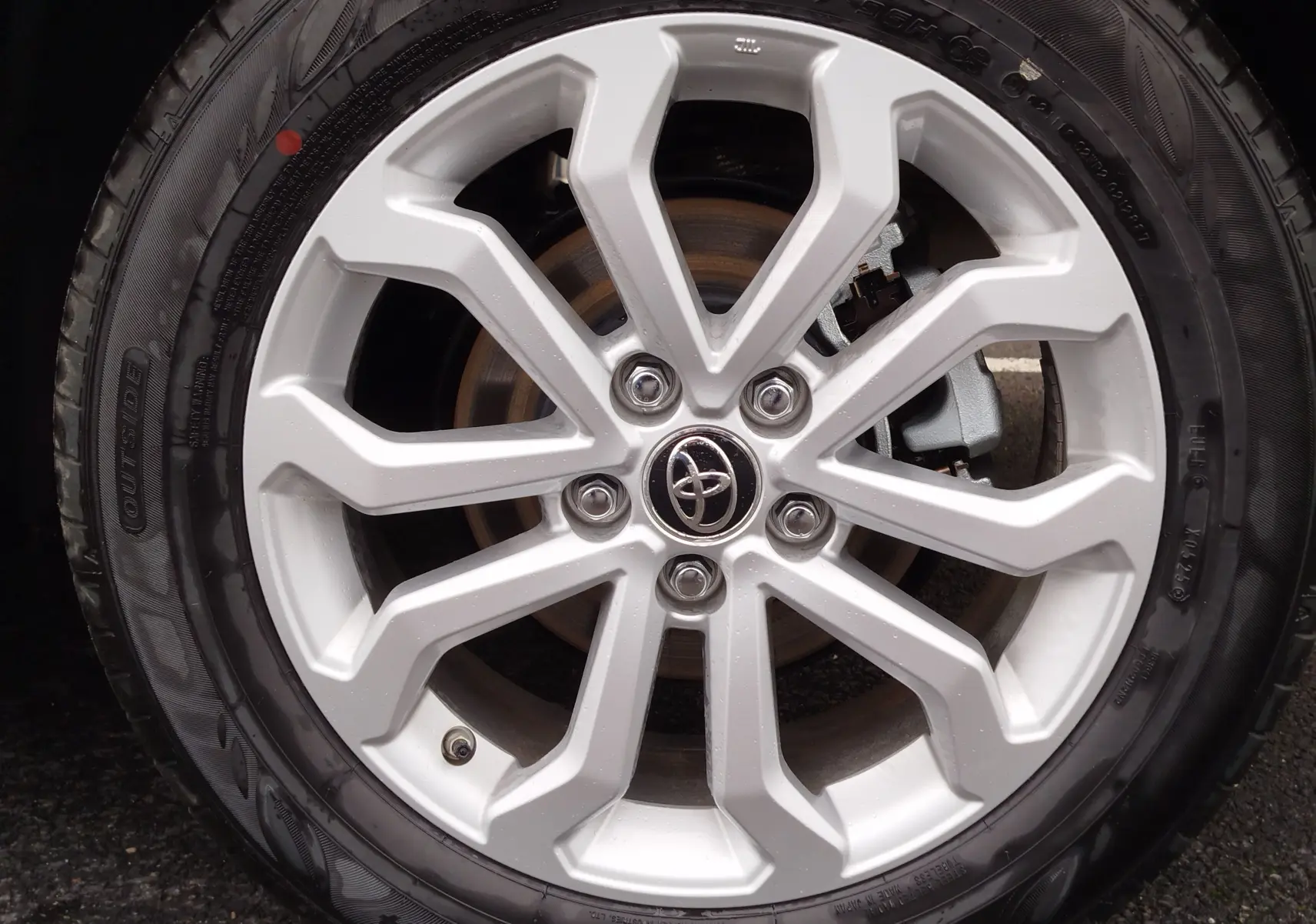 Gros plan sur la jante argentée en alliage avec logo Toyota au centre du Toyota Corolla Cross noir intense 2025.