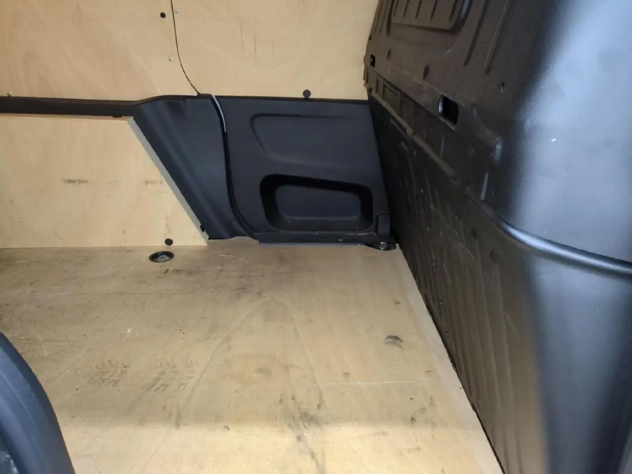 Vue intérieure de la zone de chargement du Citroën Berlingo gris clair avec plancher bois antidérapant et parois noires.