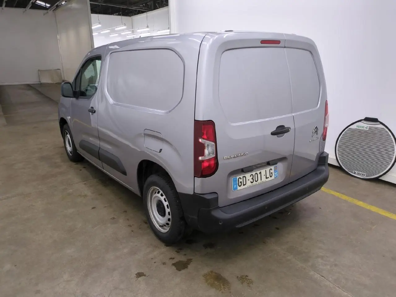 Vue 3/4 arrière droite d'un Citroën Berlingo gris clair fourgon avec portes arrière battantes et jantes tôle.
