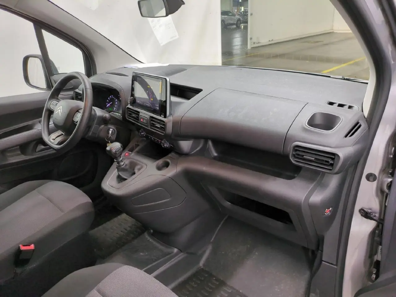 Vue intérieure côté passager du tableau de bord gris foncé du Citroën Berlingo 2021 avec écran tactile central et volant moussé.