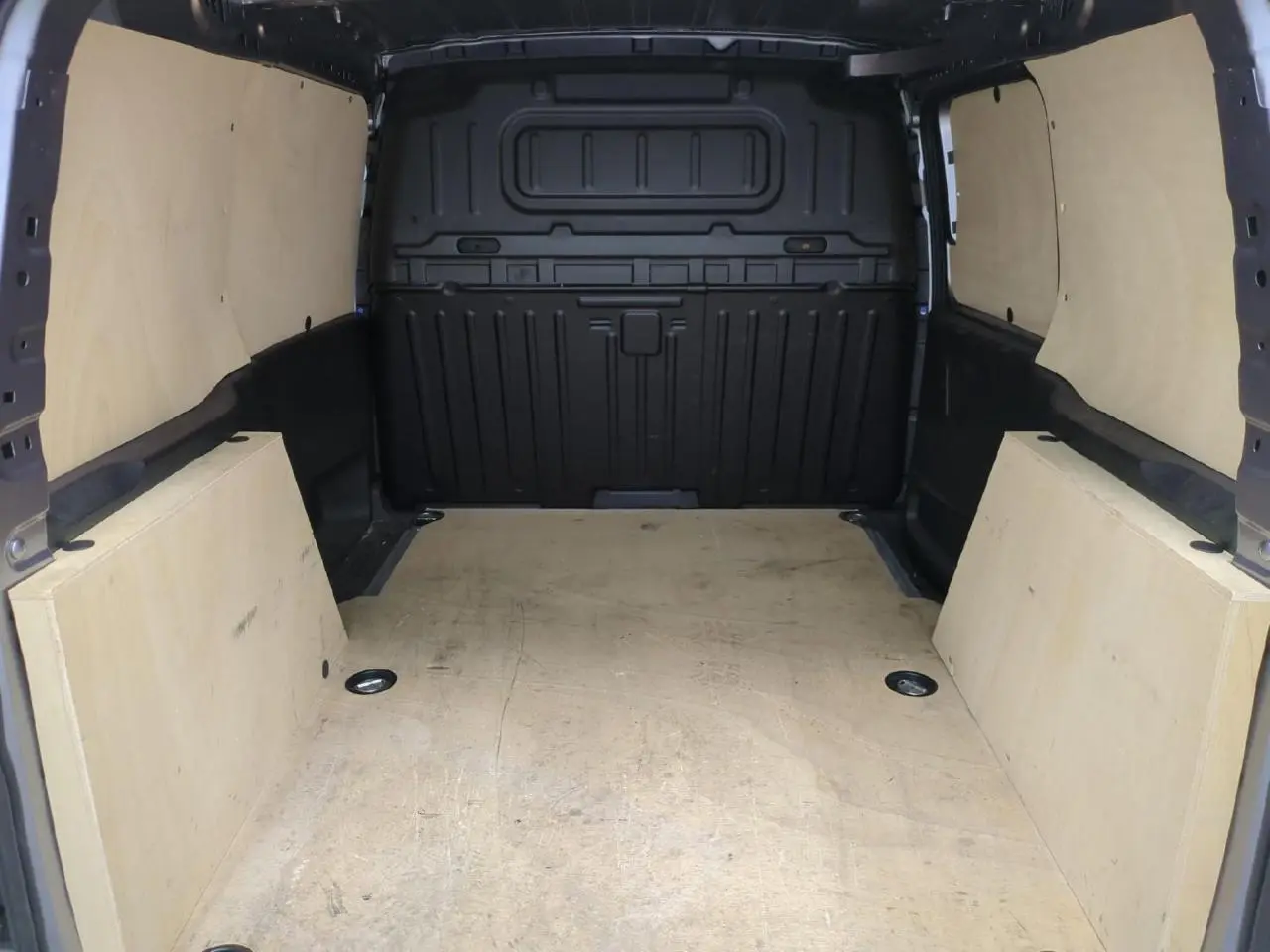 Vue intérieure arrière du fourgon Citroën Berlingo gris clair avec plancher bois antidérapant et parois protégées.