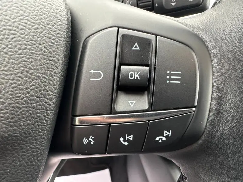 Gros plan sur les commandes multifonctions noires du volant cuir du Ford Kuga 1.5 EcoBoost Titanium 2024.