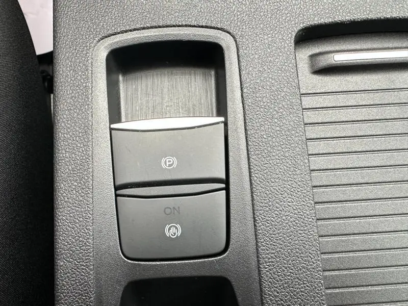 Gros plan sur le bouton de frein à main électronique dans l'habitacle du Ford Kuga 2024 gris Solar Métallisé.