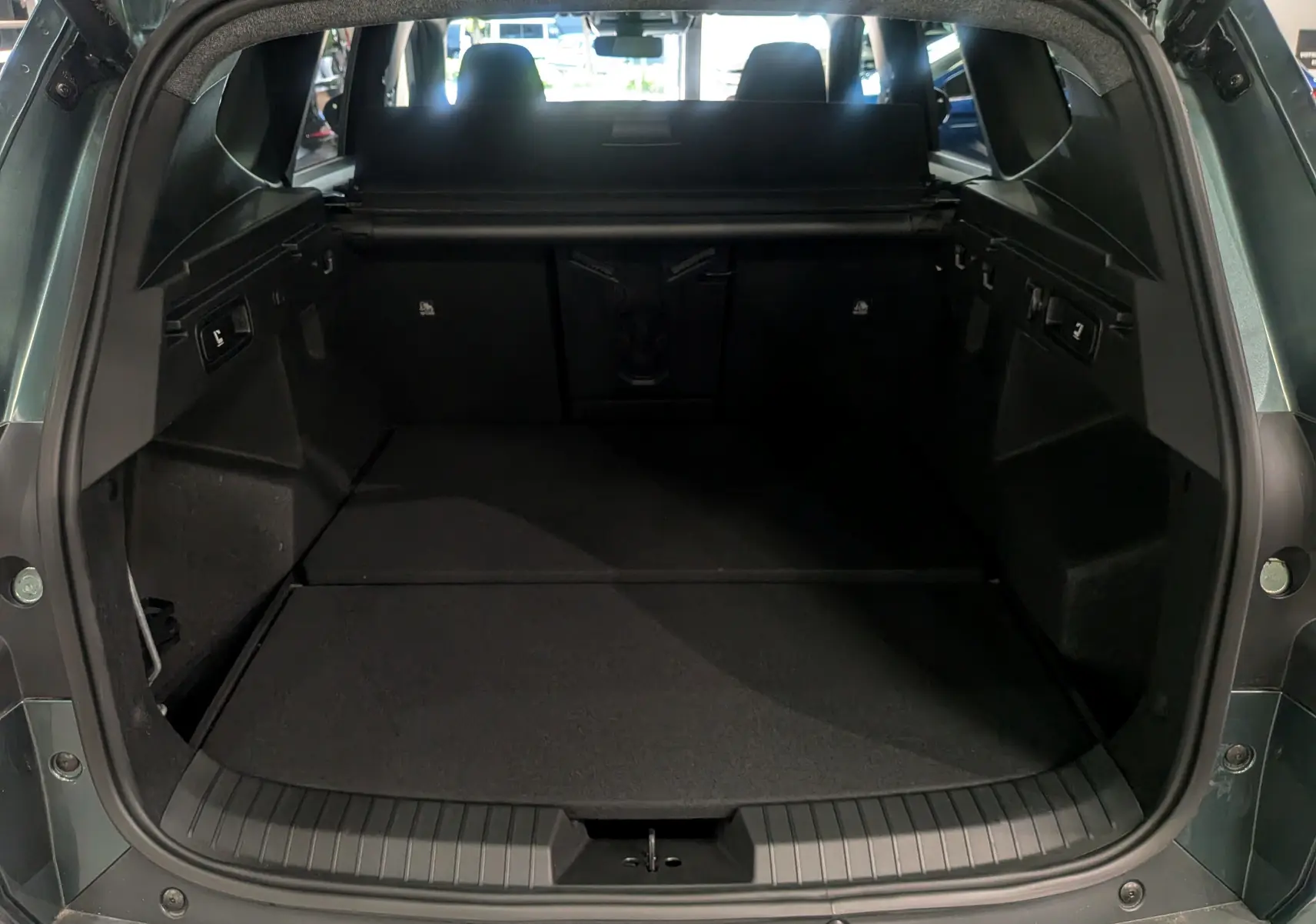 Vue arrière du coffre ouvert du Dacia Bigster Vert Cèdre, montrant un espace de chargement spacieux et noir.