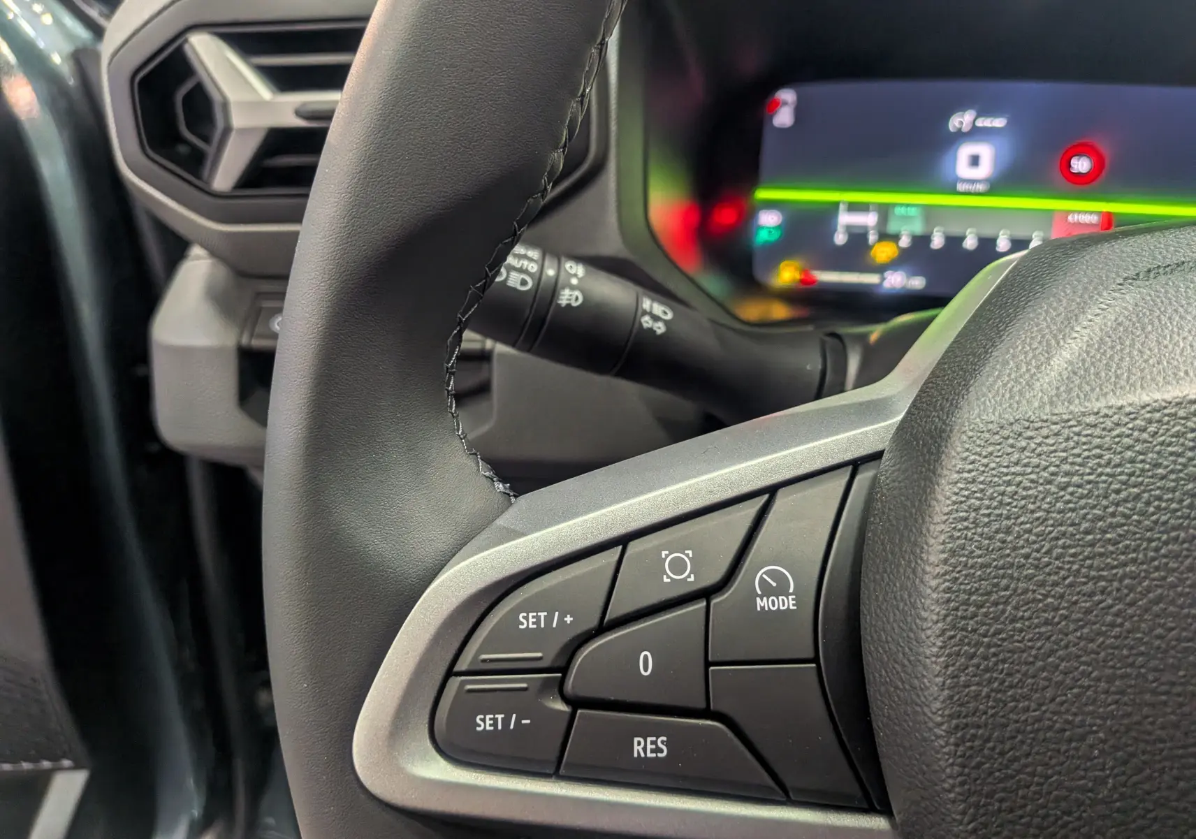 Gros plan sur les commandes au volant du DACIA Bigster 2026, avec tableau de bord numérique en arrière-plan.