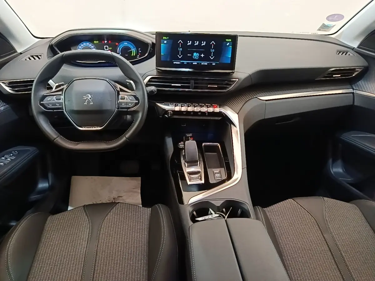 Vue intérieure du tableau de bord et volant cuir noir du Peugeot 3008 hybride rechargeable 2023, avec écran tactile central.