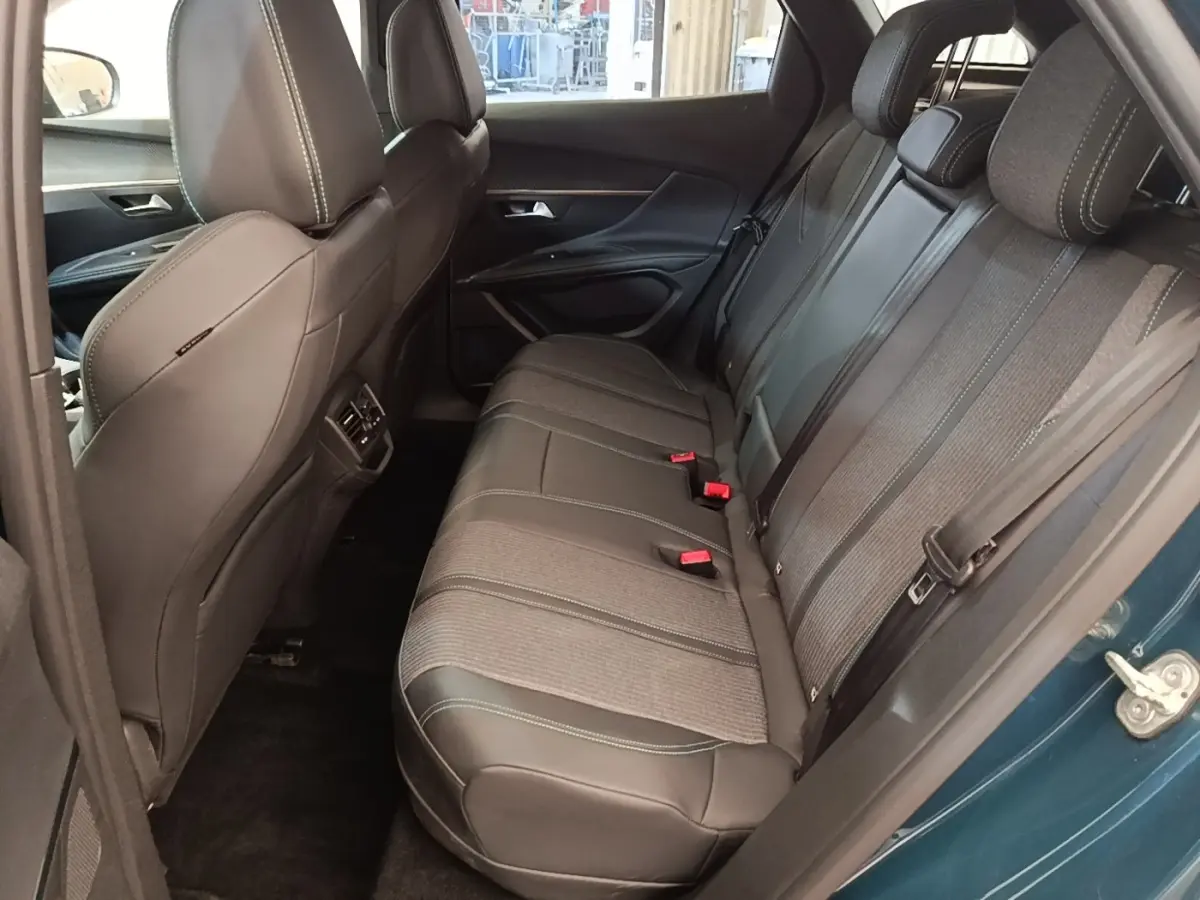 Vue intérieure côté arrière droit du Peugeot 3008 bleu 2023, montrant la banquette arrière en tissu et cuir avec ceinture de sécurité.