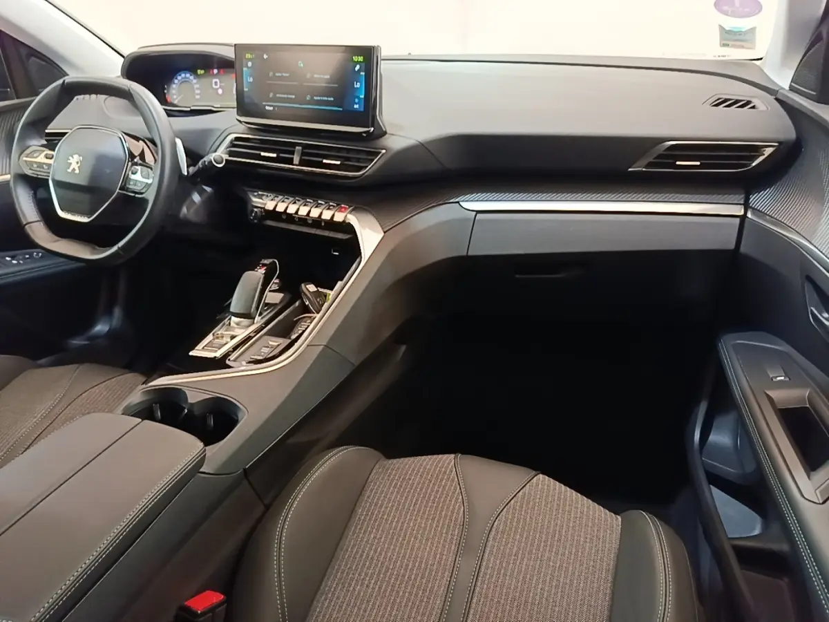 Intérieur avant droit du Peugeot 3008 bleu 1.6 HYBRID 225 Allure 2023, volant cuir et écran tactile central visible.