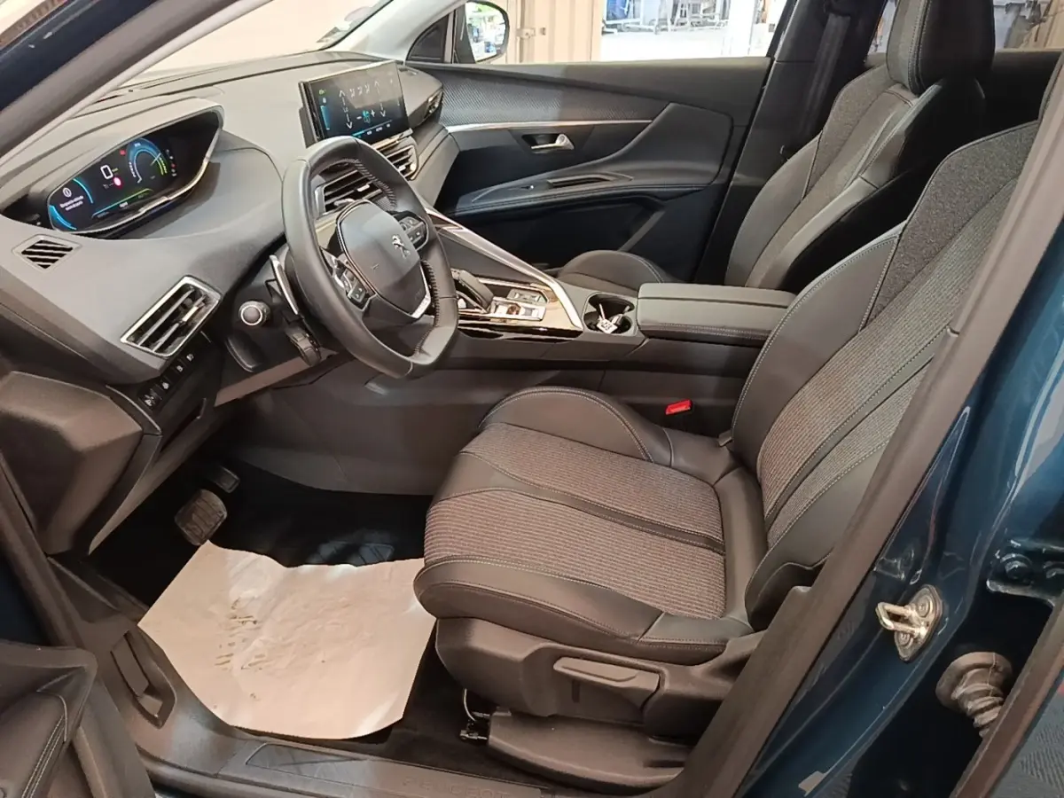 Vue intérieure côté conducteur du Peugeot 3008 bleu 2023, avec volant cuir multifonctions et tableau de bord numérique.