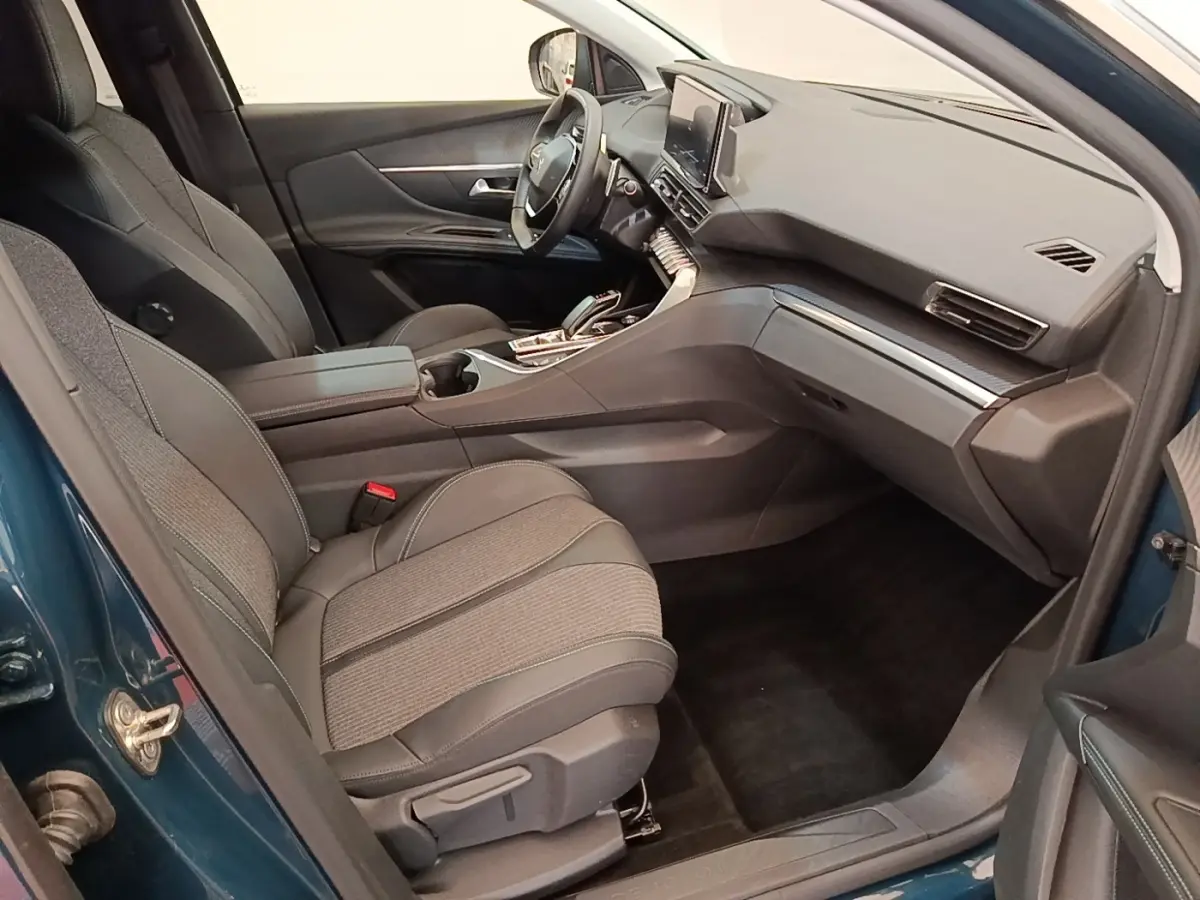 Vue intérieure côté passager du Peugeot 3008 bleu 2023, montrant sièges tissu/cuir et tableau de bord moderne.