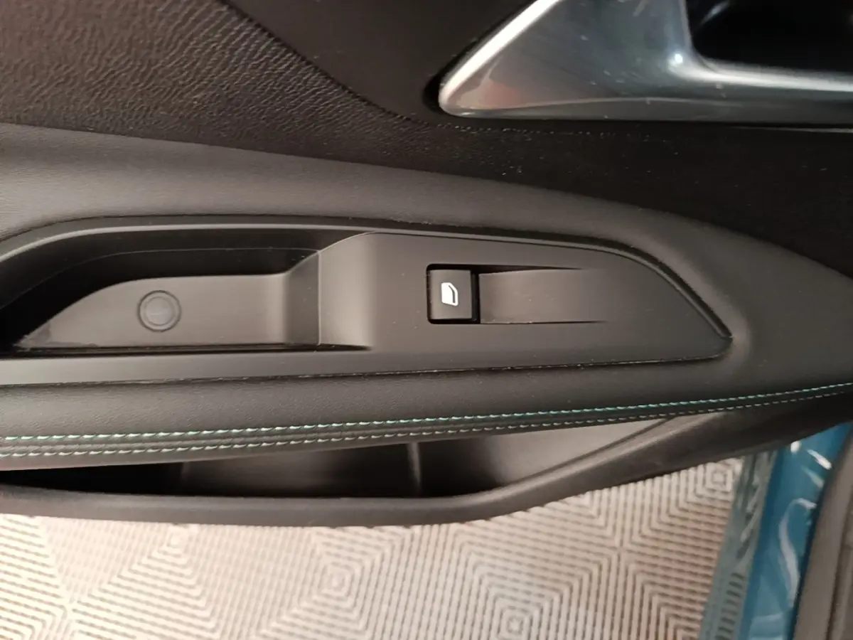Gros plan sur la commande d’ouverture de trappe à carburant sur la porte côté gauche d’un Peugeot 3008 bleu.