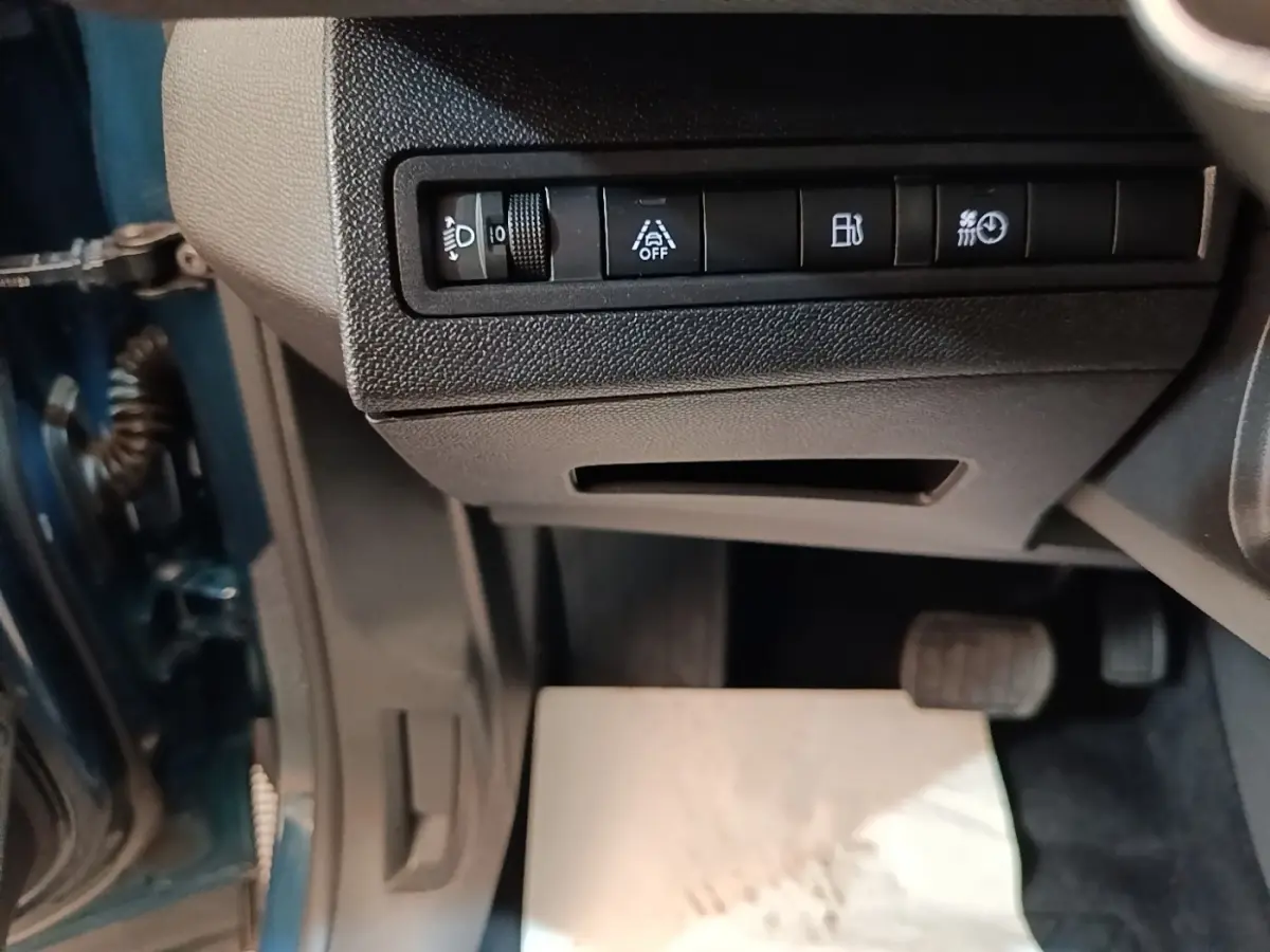 Vue intérieure côté conducteur du Peugeot 3008 bleu, montrant les commandes sous le tableau de bord et les pédales.