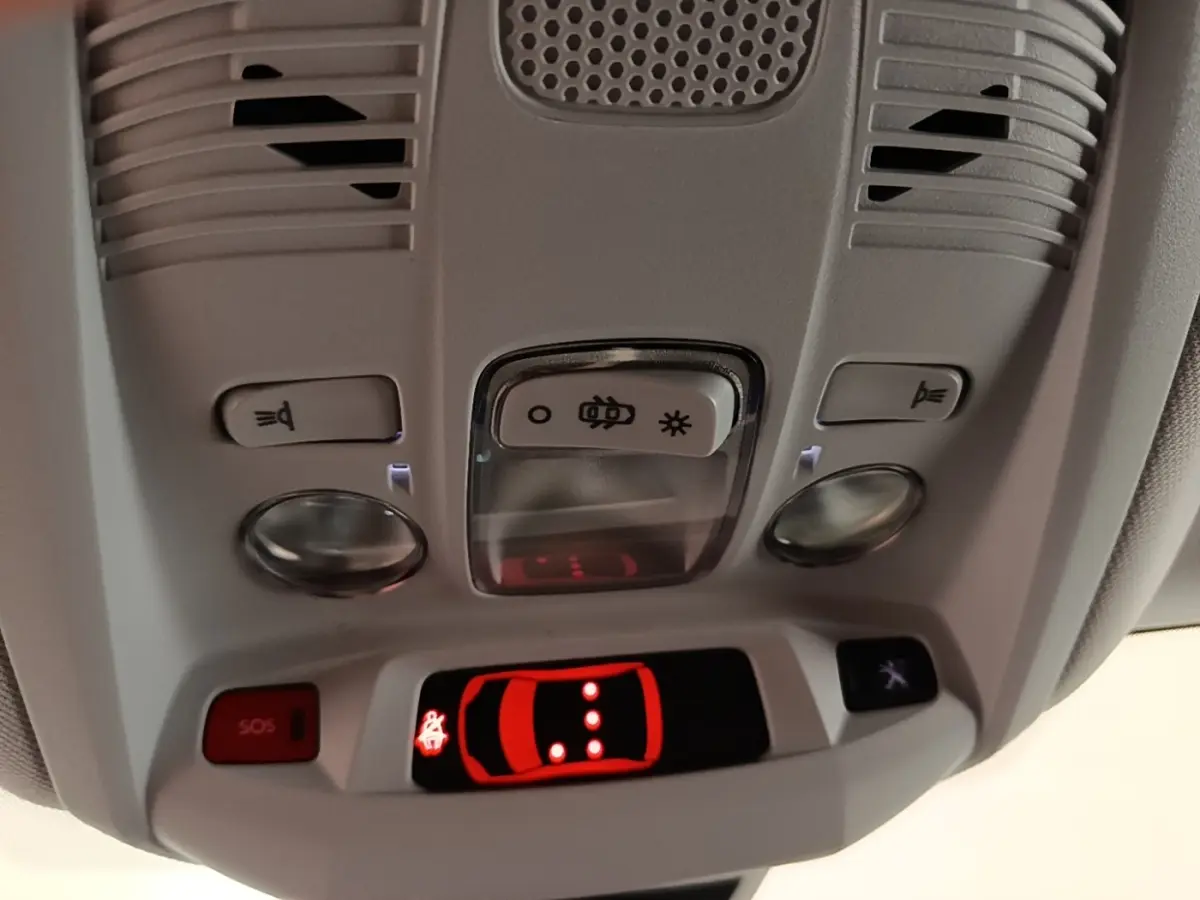 Vue rapprochée du plafonnier gris clair du Peugeot 3008 2023 avec boutons d’éclairage et alerte SOS rouge allumée.
