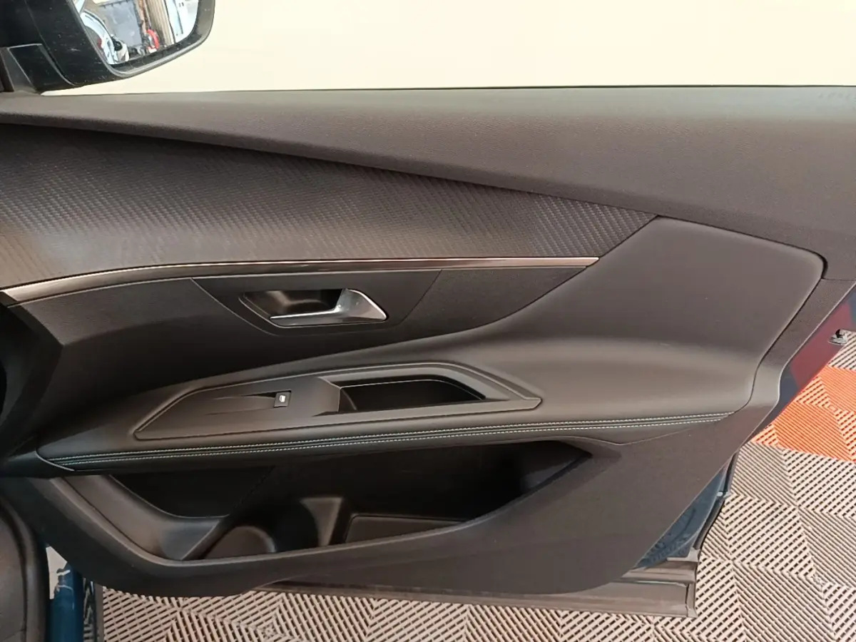 Vue rapprochée de la porte avant gauche du Peugeot 3008 bleu, avec garniture noire et surpiqûres blanches.