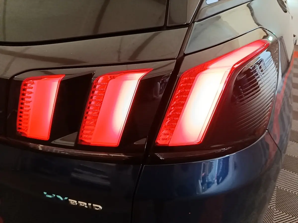 Gros plan sur le feu arrière droit rouge du Peugeot 3008 bleu hybride rechargeable, avec logo HYBRID visible.