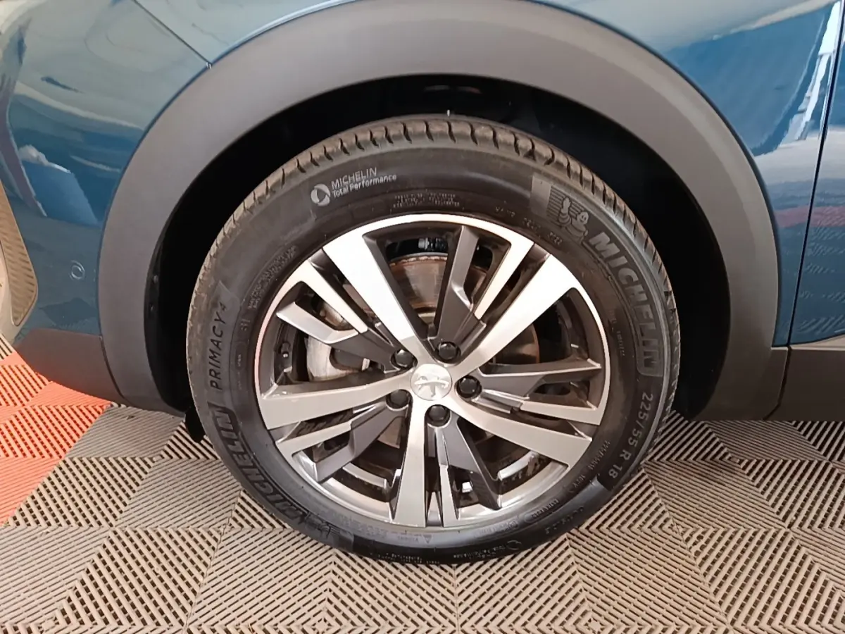 Gros plan sur la roue avant gauche du Peugeot 3008 bleu 2023 avec jante alliage et pneu Michelin.
